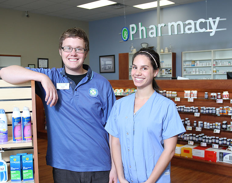 photo of pharmacy technicians in front of pharmacy sign